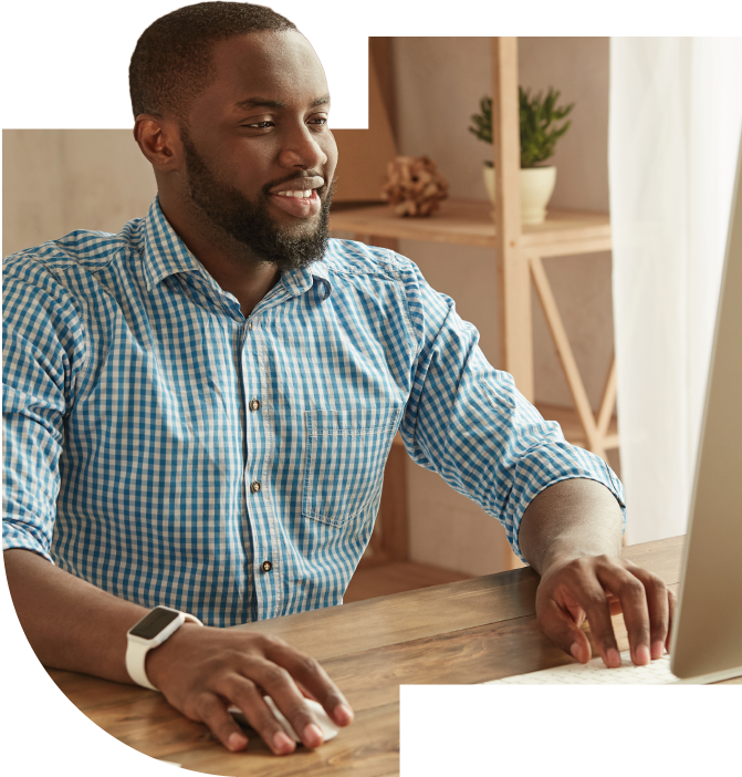 Un homme devant un ordinateur avec le sourire aux lèvres.
